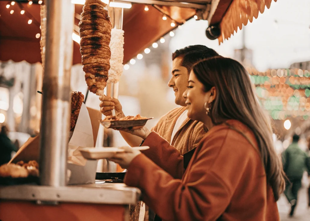 Pareja disfrutando tacos al pastor en un mercado mexicano. Mejor comidas en viaje en pareja